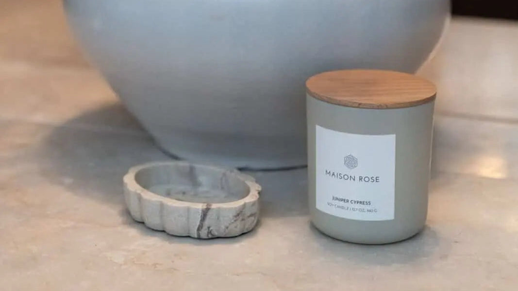 Gray vase with greenery, candle, and ring on a surface
